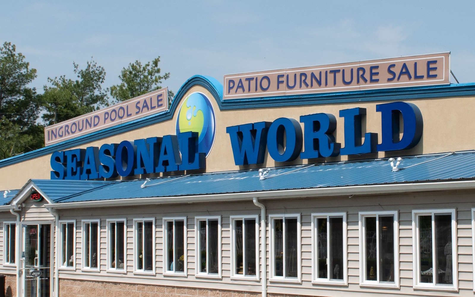 Seasonal World storefront signage &mdash; SEASONAL WORLD logo with INGROUND POOL SALE and PATIO FURNITURE SALE banners