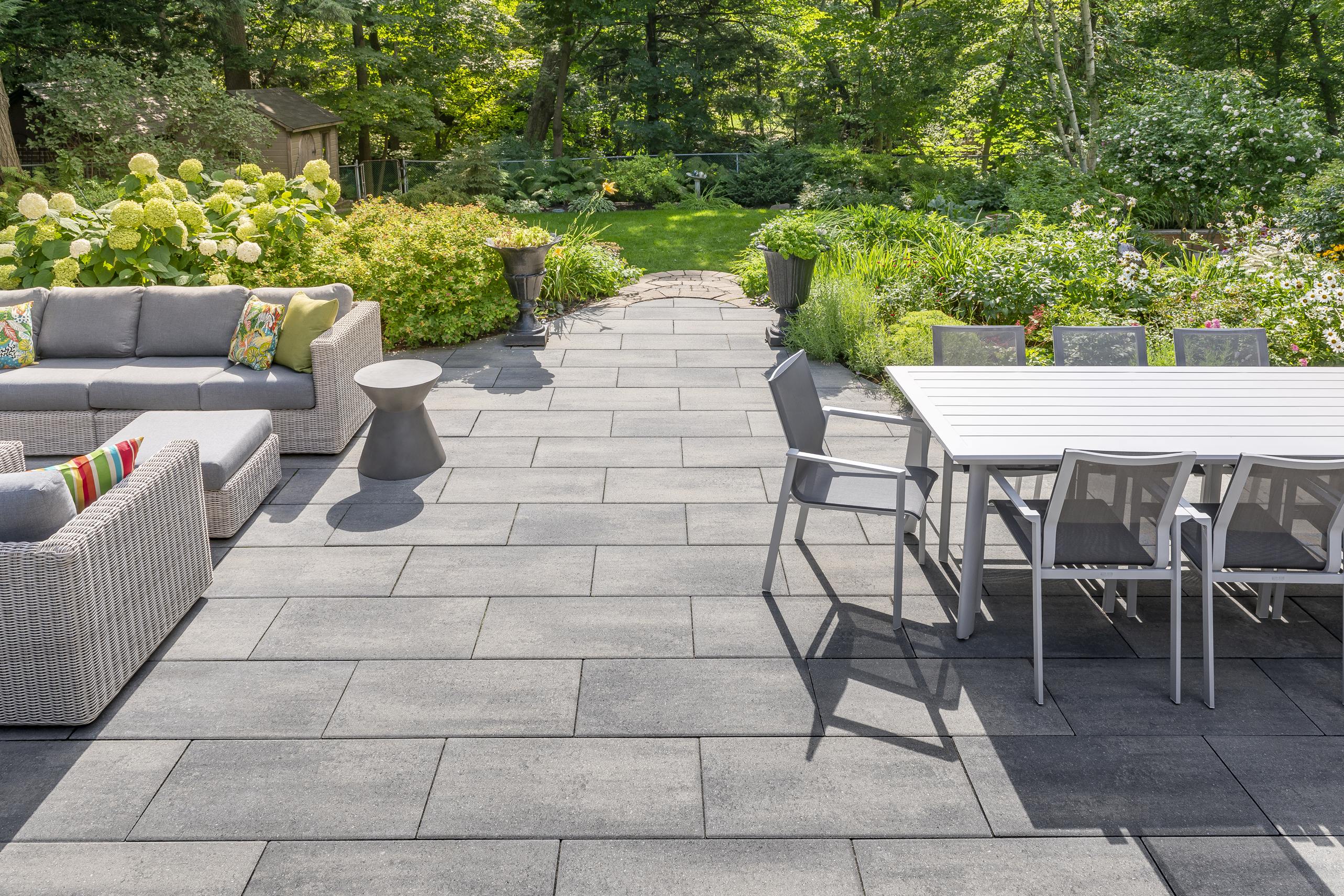 Modern paver patio at dusk with Rinox PROMA XL slabs in Ash Charcoal, fire feature, and outdoor seating