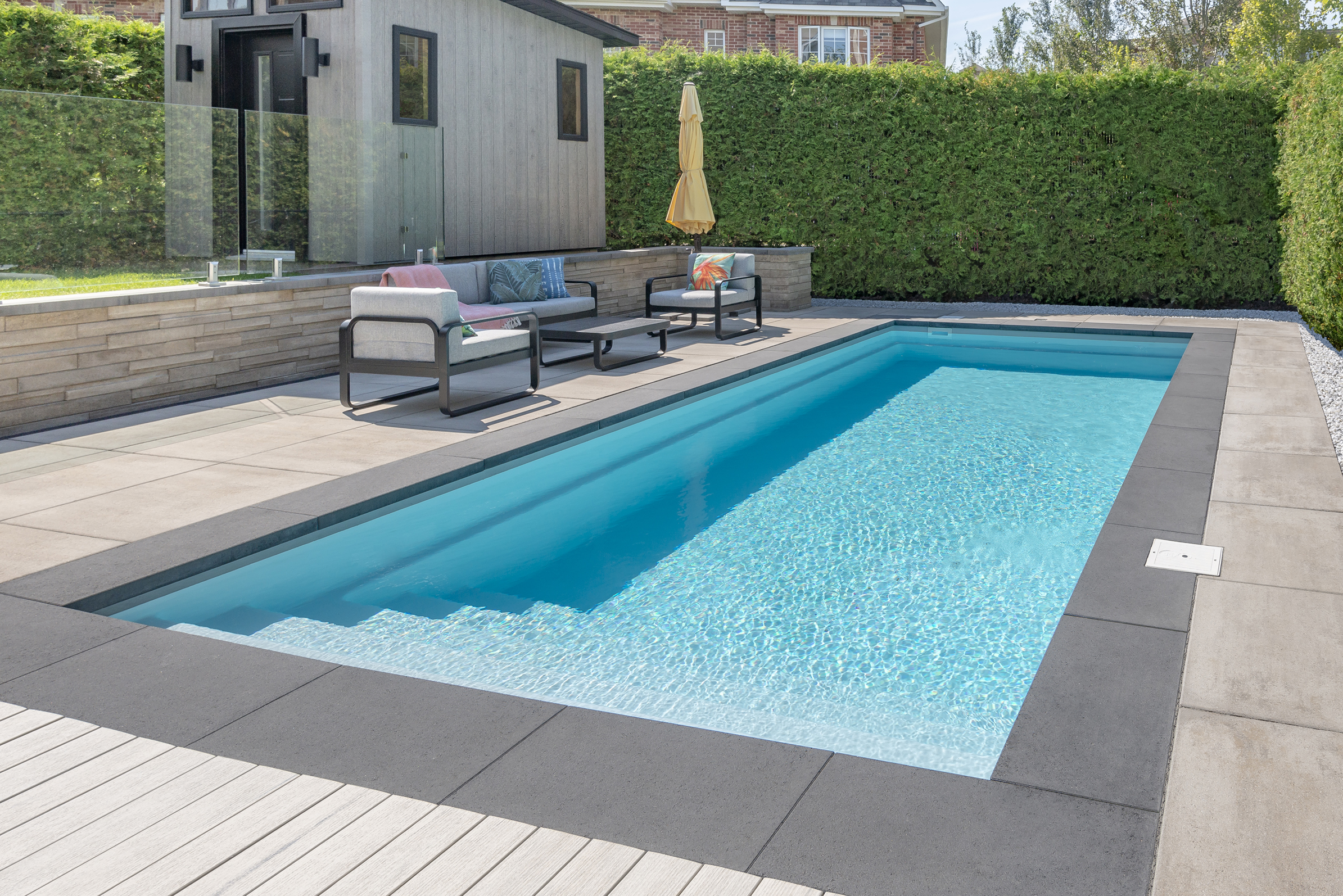 Rinox PROMA XL coping in Caviar finishing the edge of an Azoria Topaze fiberglass pool in Arctic Grey