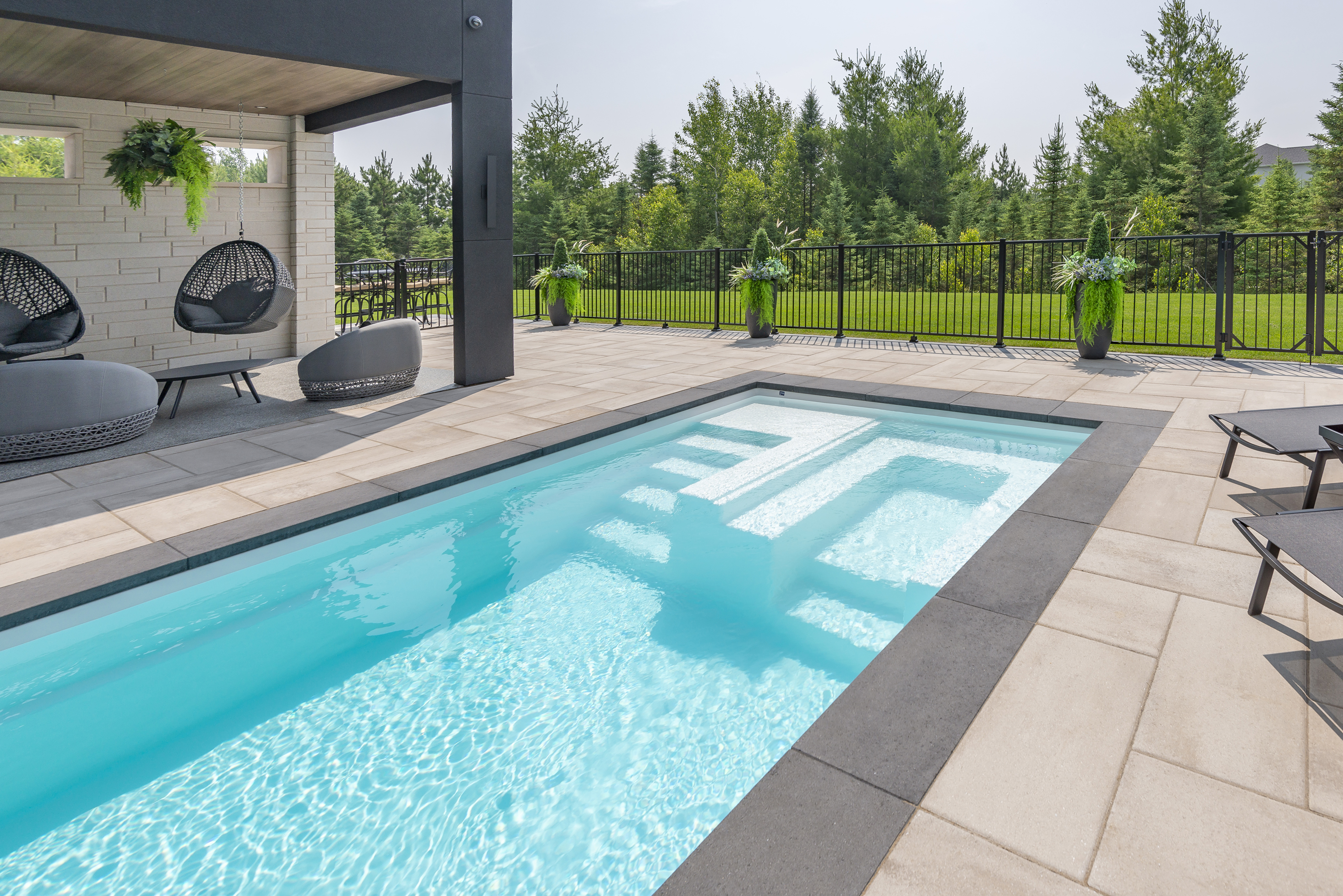 Rinox PROMA XL Coping in Caviar finishing the edge of an Azoria Lazuli fiberglass pool in Sea Salt